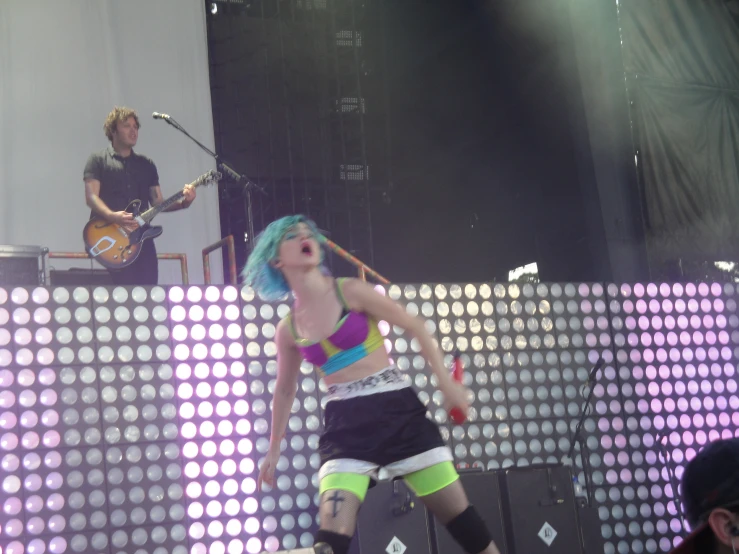 a woman wearing colorful clothes standing on stage with musical instruments