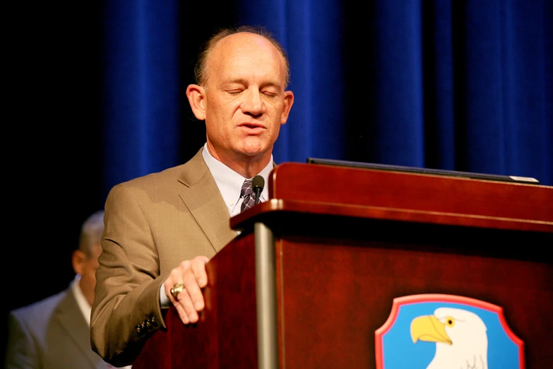 a man standing in front of a wooden podium wearing a suit