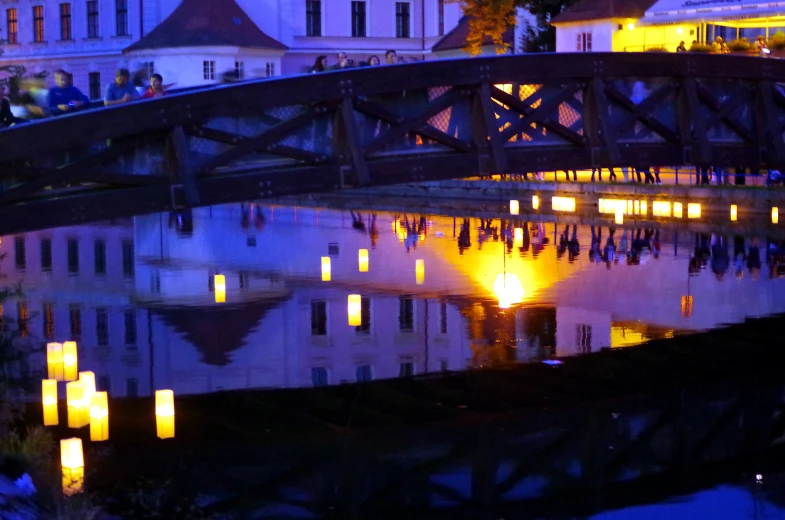 a bridge lit up with candles by some water