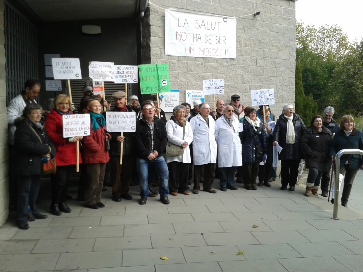 a group of people holding signs standing together on a sidewalk