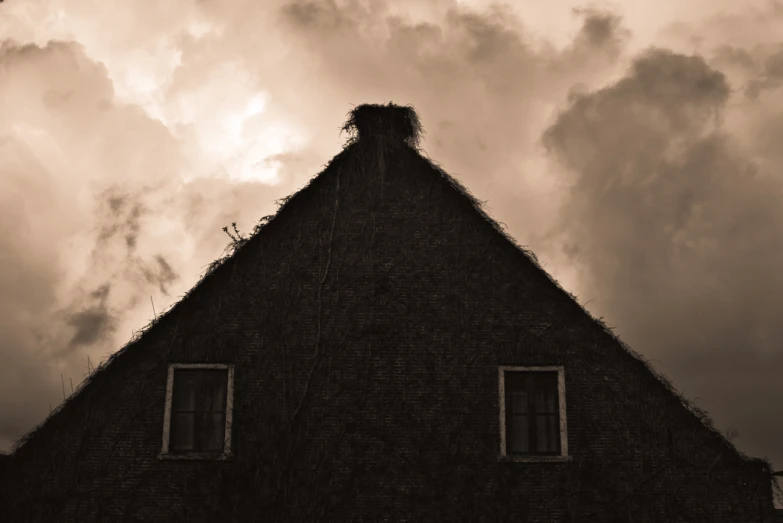 clouds hang overhead on a building that has two windows