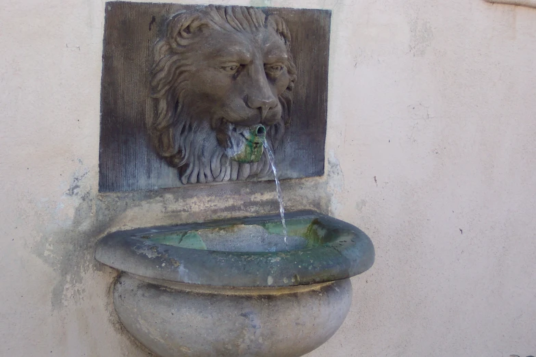 a stone lion head is over a water fountain