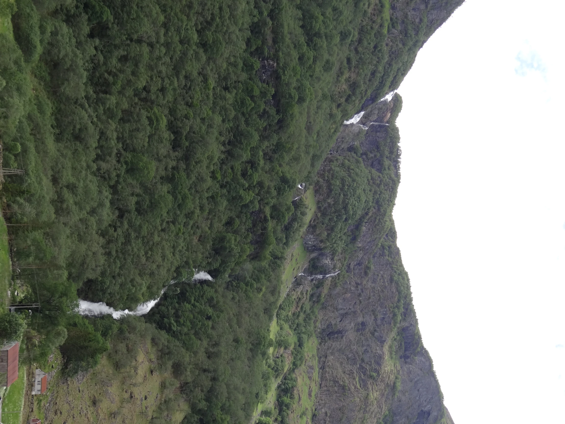 a view of mountains, stream, and small house