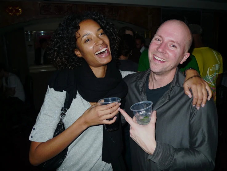 a smiling woman and a bald man at a party