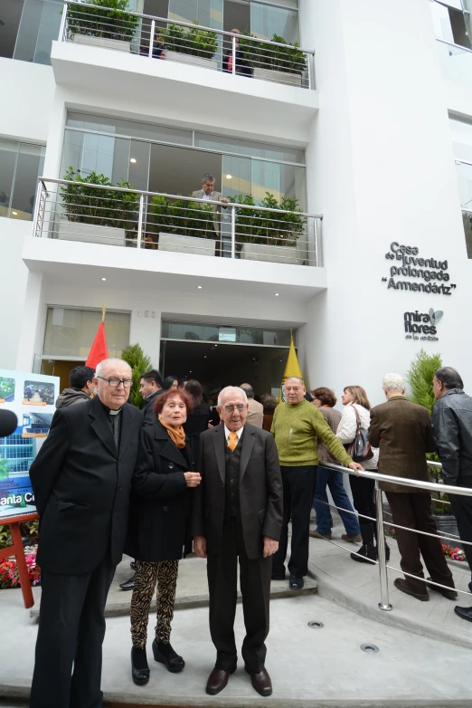 the two men in black are standing by a white building