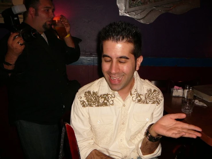 a man in a white shirt and jeans smiling while seated