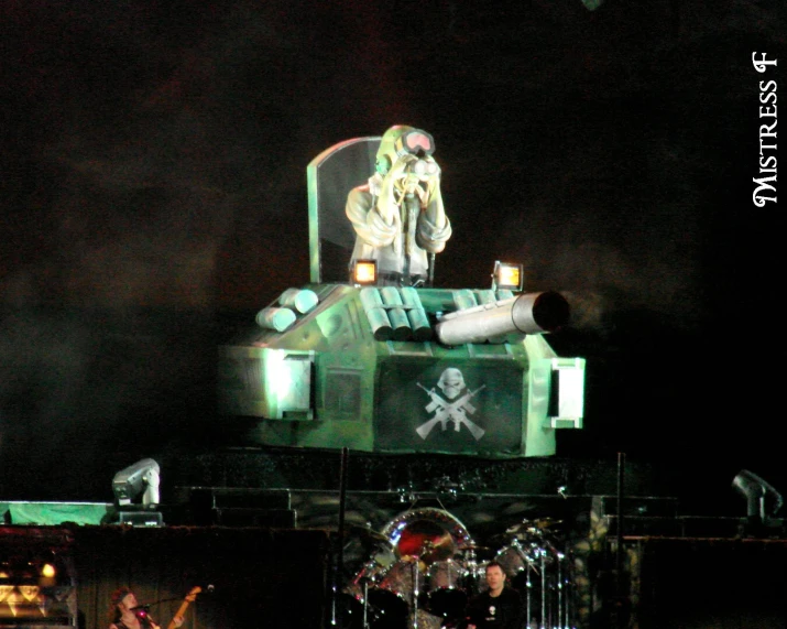 a man standing on top of a green tank with a guitar