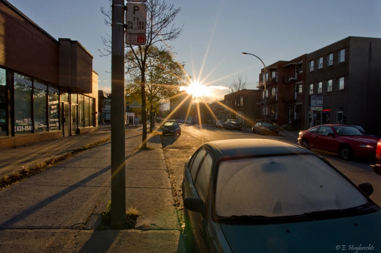 cars are parked along a city street at sunset