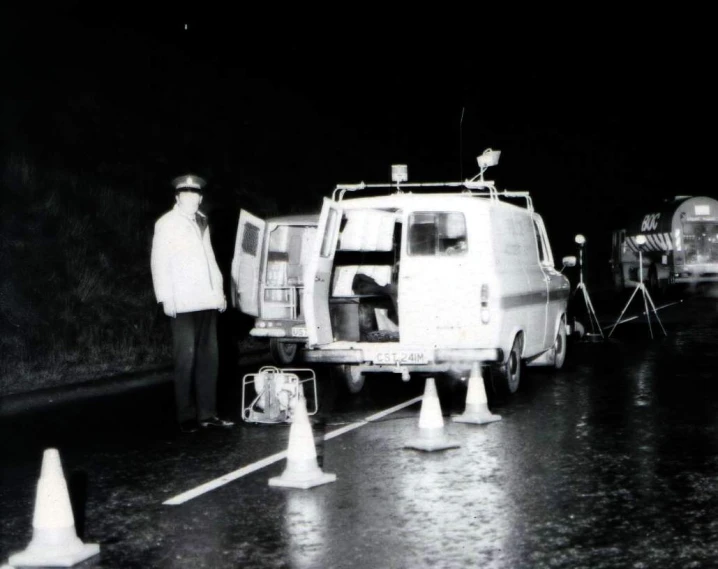 a black and white po of two men standing next to police cars