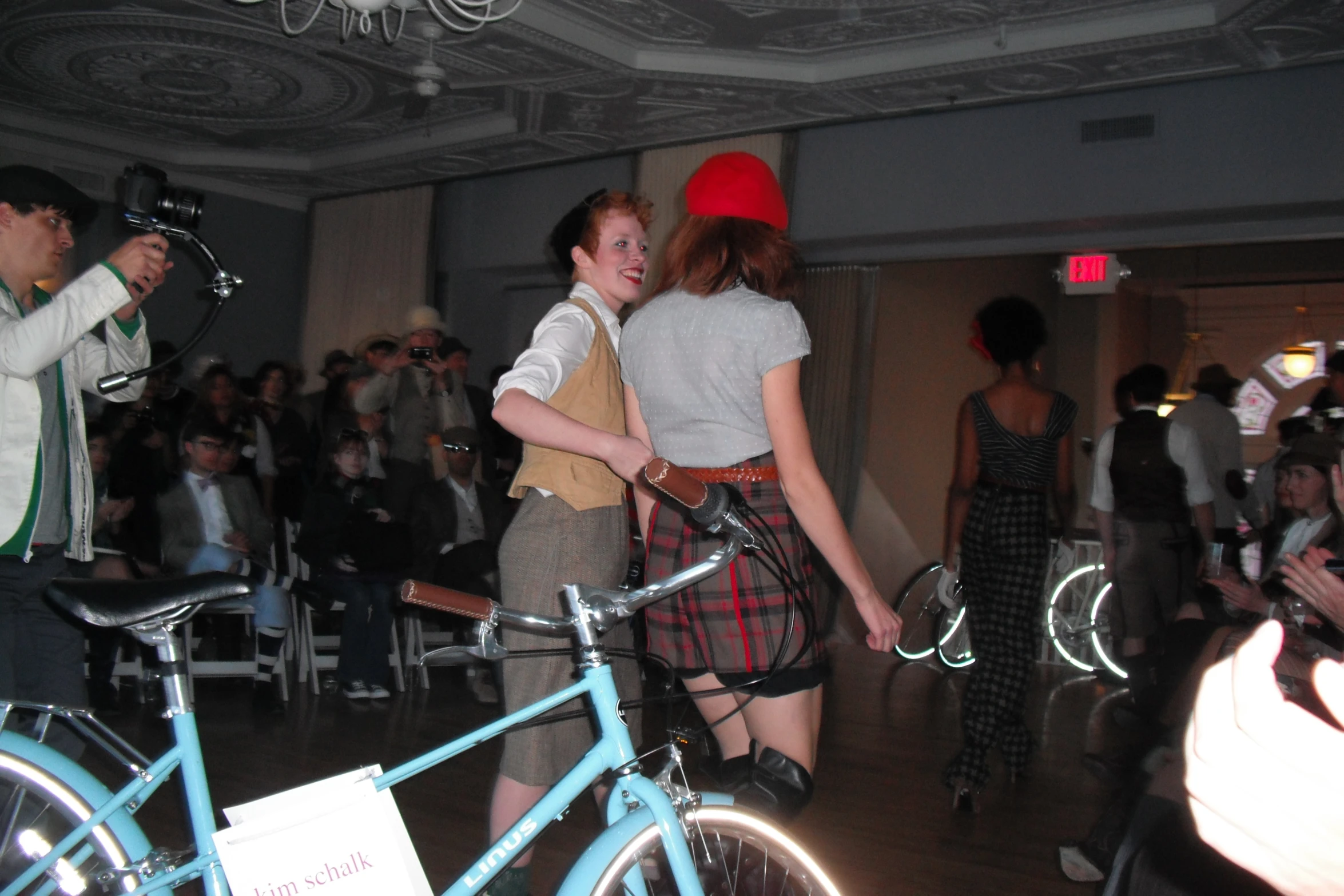 two people with plaid clothes and red hats dancing with their bicycles