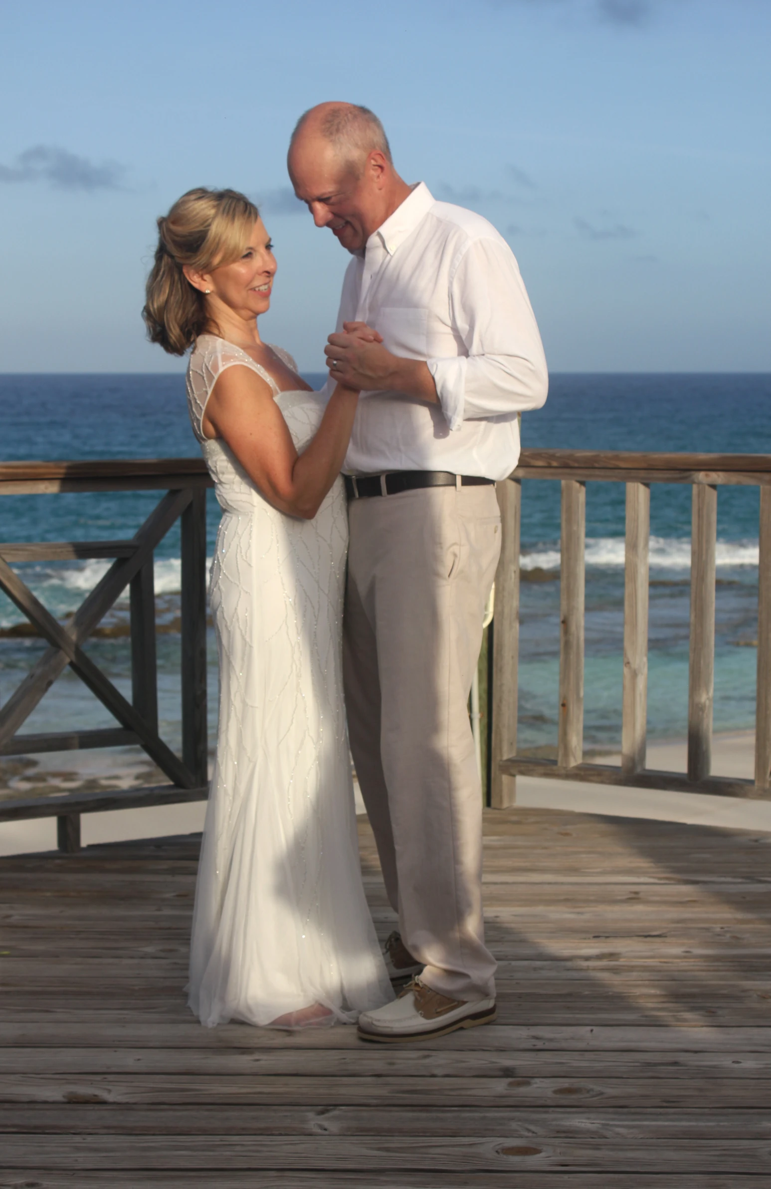 a man and a woman on a wooden deck near the ocean