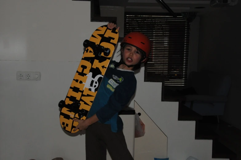a boy holding up a skateboard while wearing a helmet