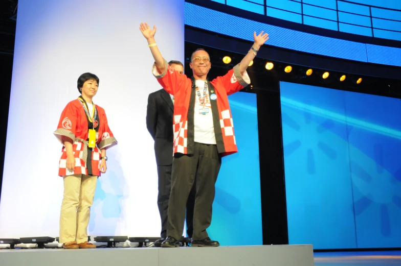 two men are standing on a stage and raising their hands