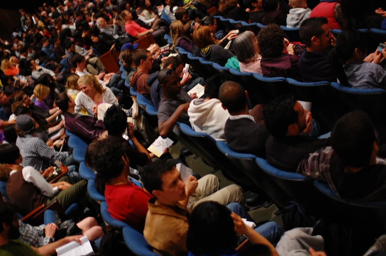 people in rows sitting in large auditorium seats