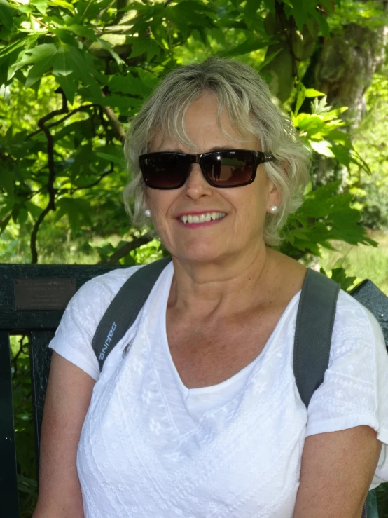 a person with a backpack and sunglasses sitting on a bench