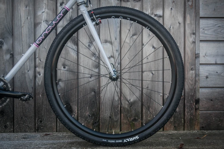 a bike wheel leaning against a wood fence
