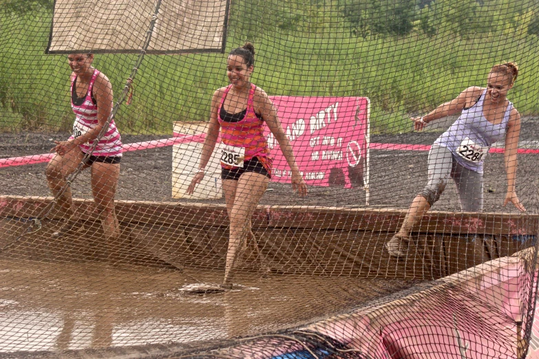 three female athletes are playing in the muddy field