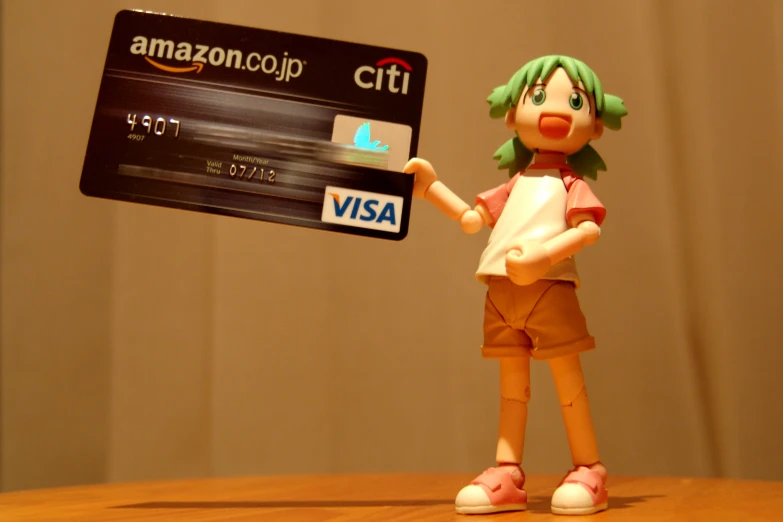 a plastic doll holds up a credit card