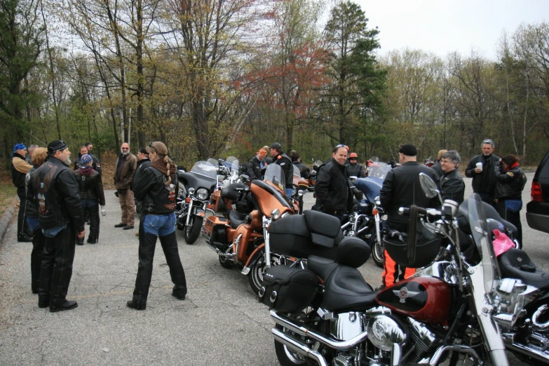 people standing in the street next to many parked motorcycles