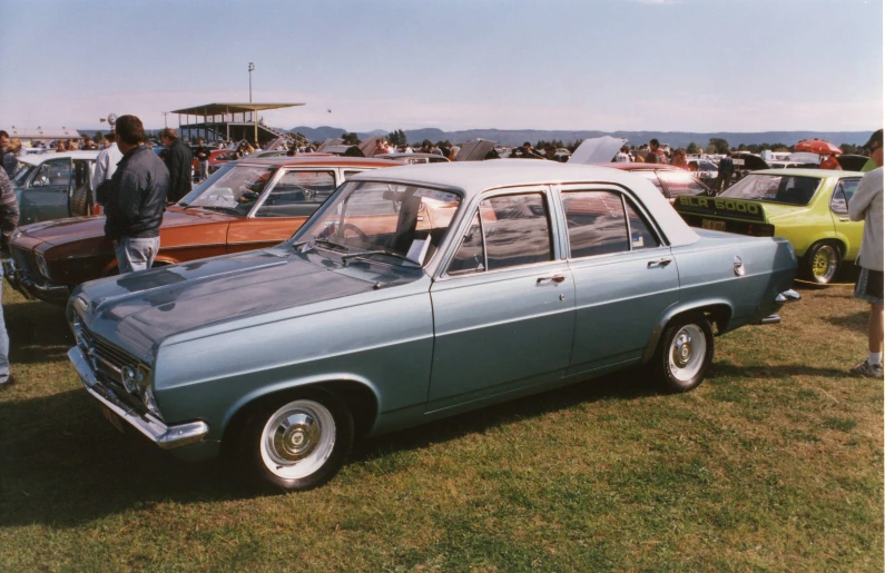 an old blue car parked in a field