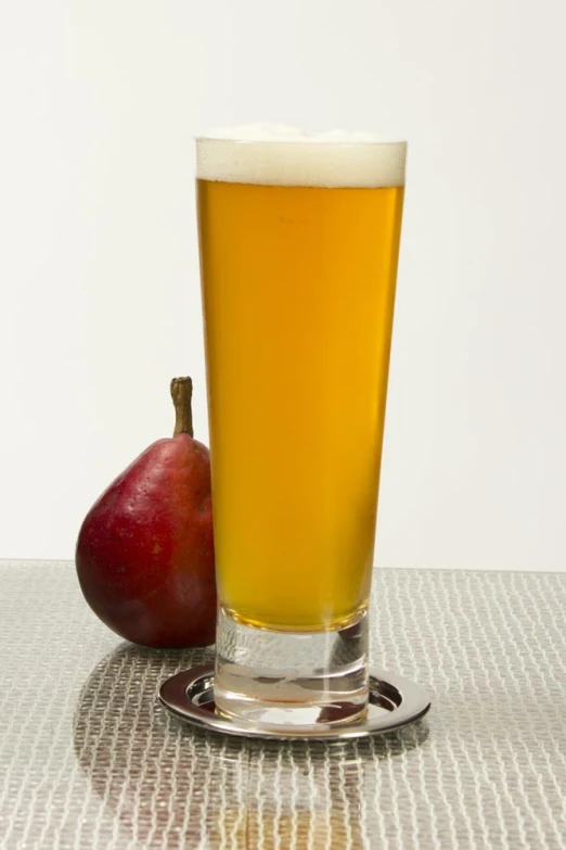 a glass of beer next to an apple