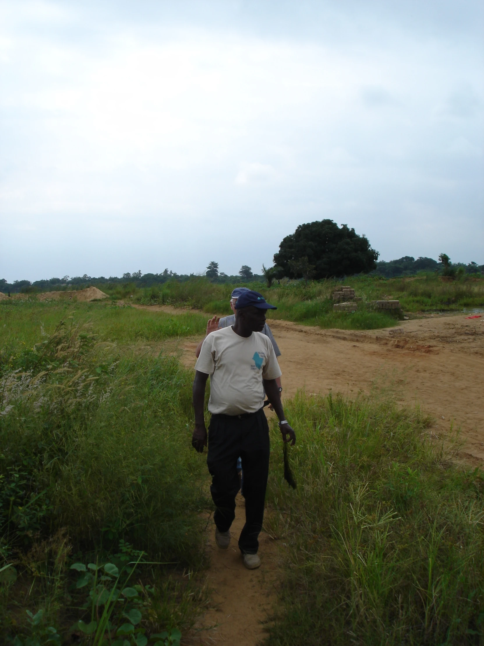 two people walking up a dirt path holding baseball bats