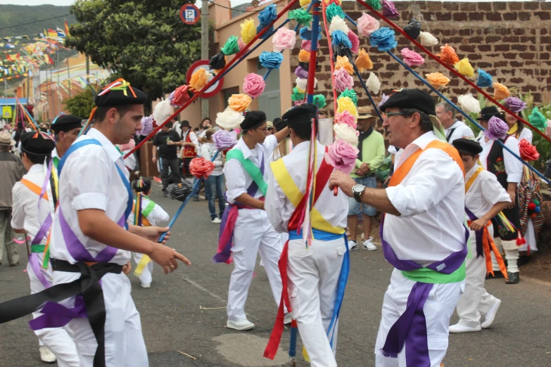 a group of men standing on the street holding colorful streamers