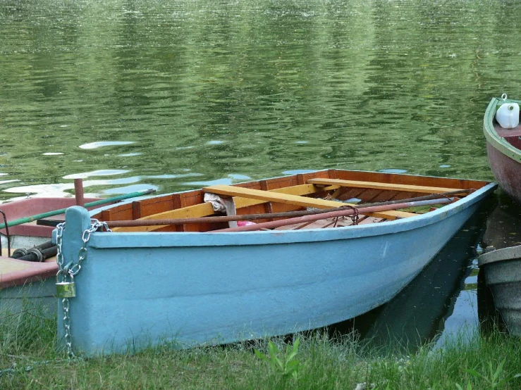 two boats sitting on the grass next to some water