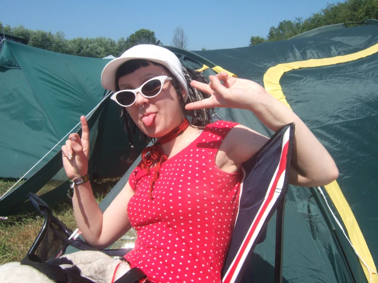 there is a woman sitting outside of a tent making a gesture