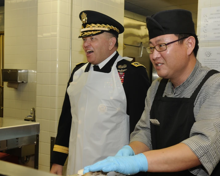 two men in uniforms are preparing food at a restaurant