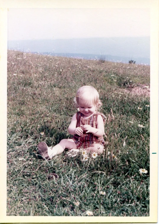 baby sitting in grass playing with a bird