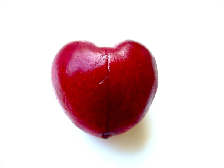 an apple in the shape of a heart on a white surface