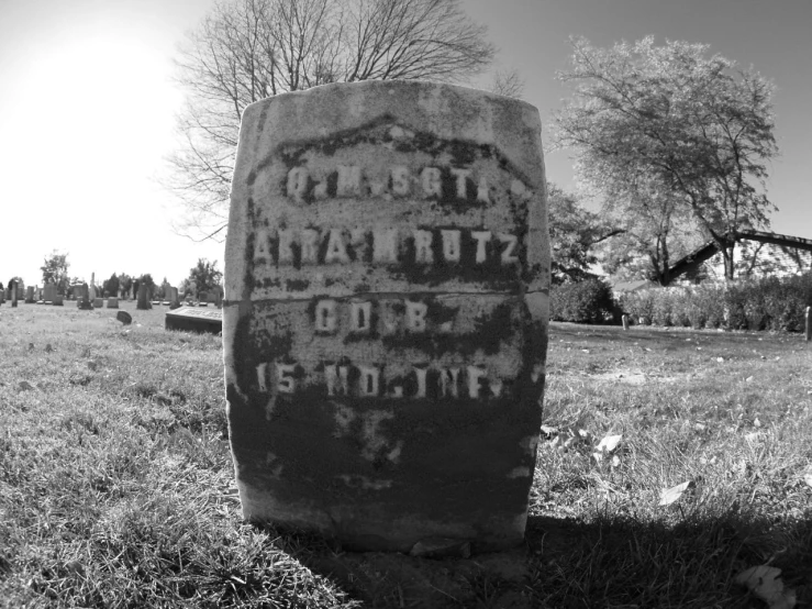 the tombstone is laying in the grass of the field