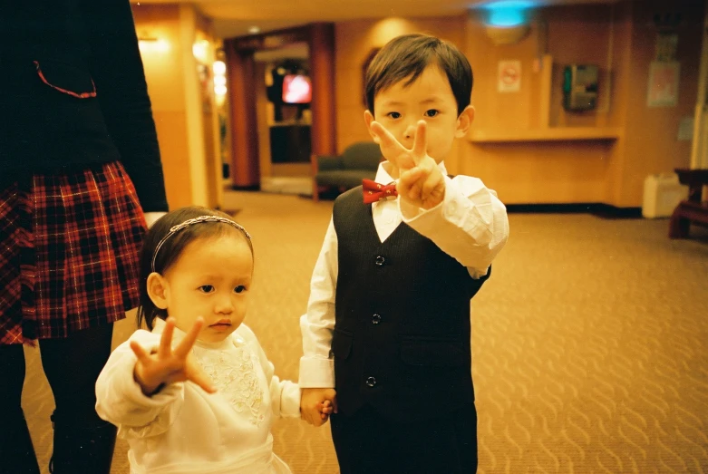 two little children making the vulcan sign in a el lobby