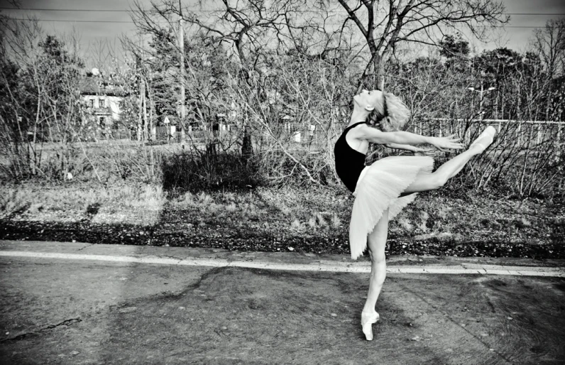 a ballerina stretching her leg to reach the pole