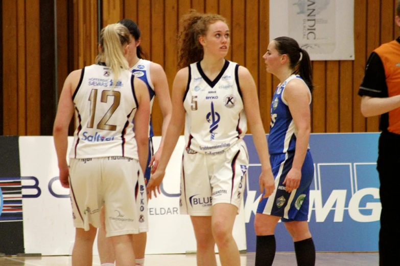 three women in uniform talking with the referee