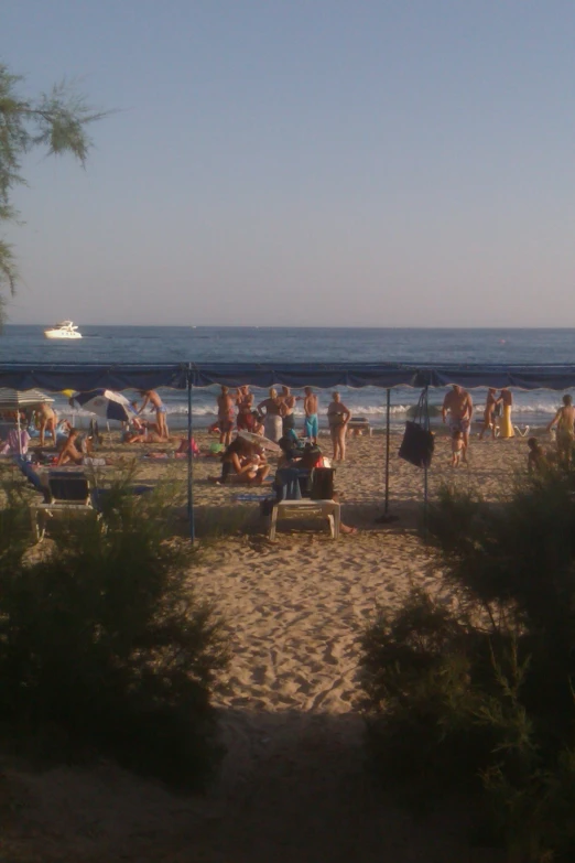 beach umbrellas are on the sand while people are sitting and standing