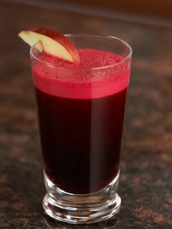 the juice is in a glass that has an apple on top