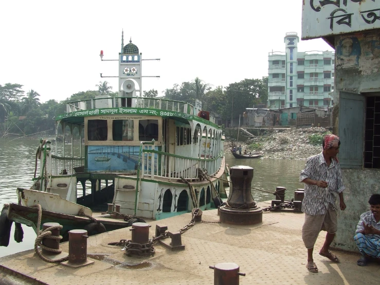 two men are standing on a dock near a ferry