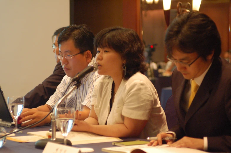 a group of people sitting at a table with notebooks and papers