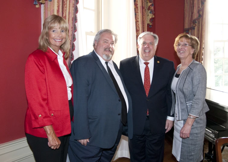 four smiling people stand next to each other in a room