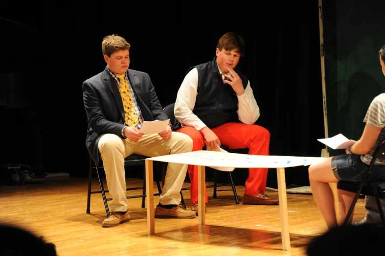 three people sitting on chairs and one of them is making a presentation