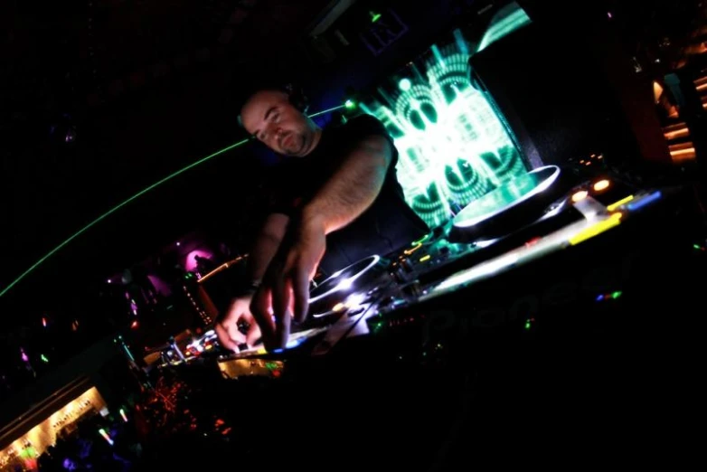 a man in the dark standing over a dj's equipment