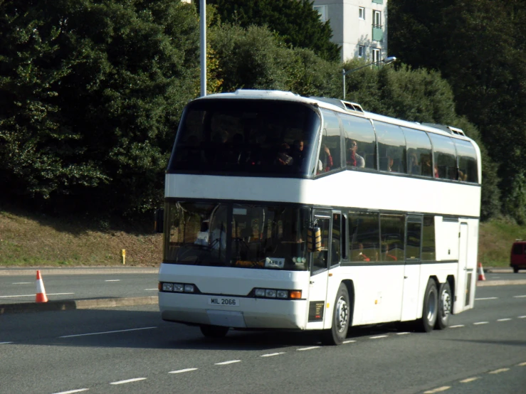 a white double decker bus driving down the street