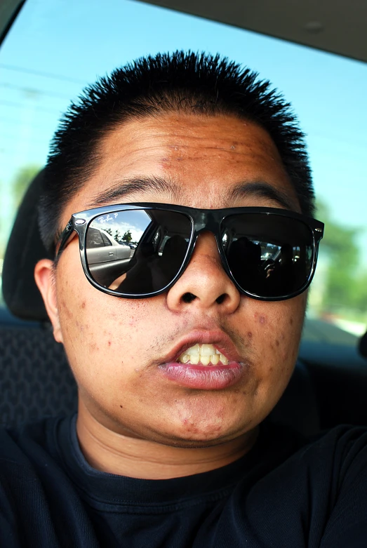 a man wearing sunglasses and black shirt in a car