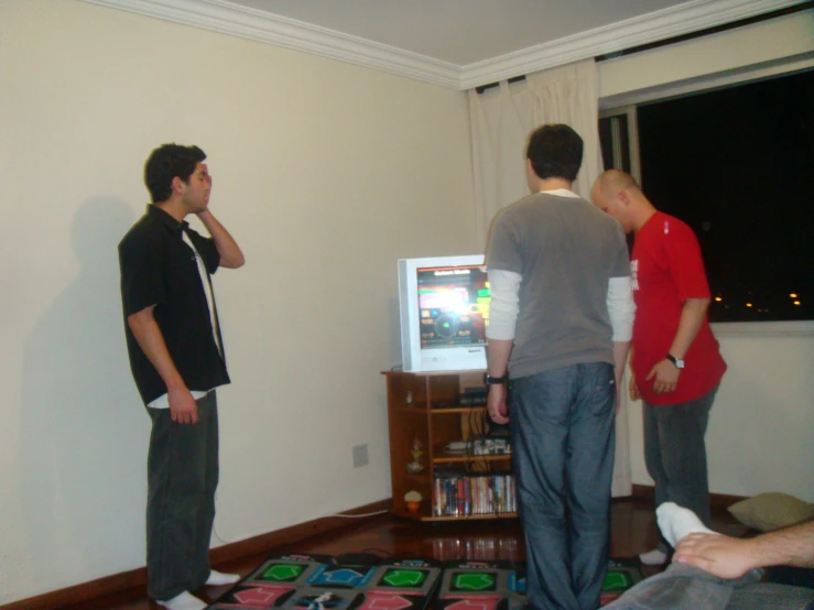 four men standing and playing video games in a living room