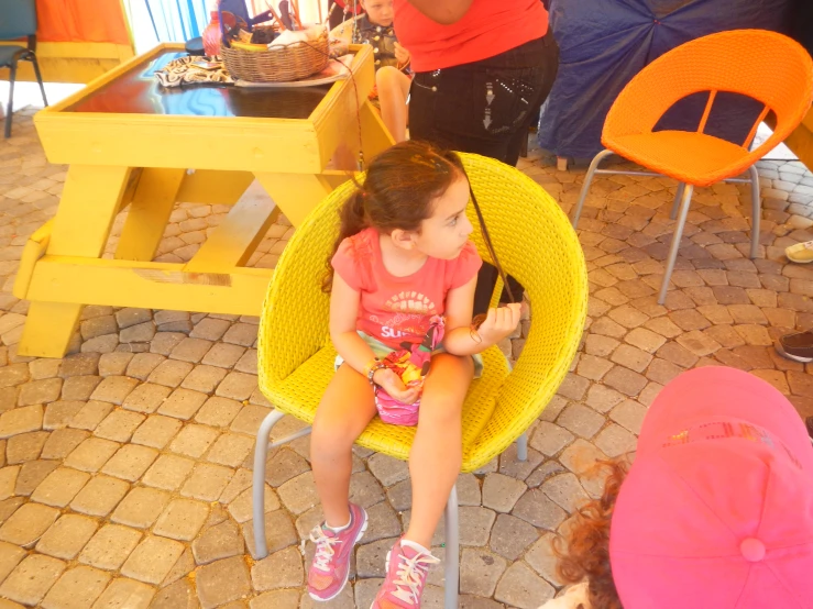 small girl sitting on chair in open area with chairs in background