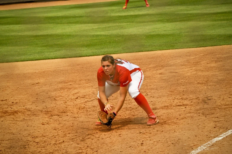 a baseball player kneeling down on the field to catch a ball