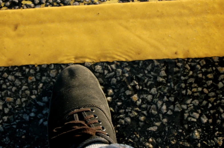 a persons shoes next to yellow curbing