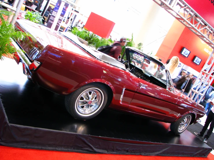 a red ford mustang sits parked in a showroom